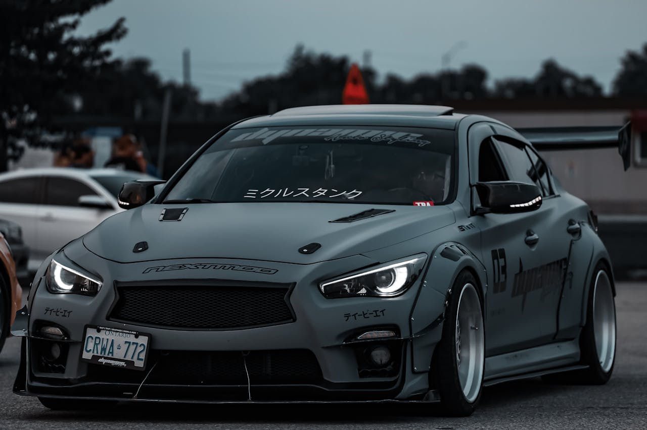 Gray sports car with modifications and decals captured during drifting in a parking lot.